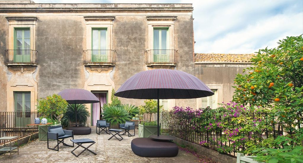 Two Beige domo shaped Bistro Umbrellas with fabric shade and steel leg on a terrace.