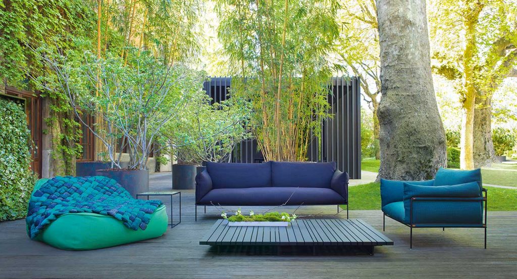 Kabà Armchair, cover in blue polyester, structure and four legs in black steel in a terrace.