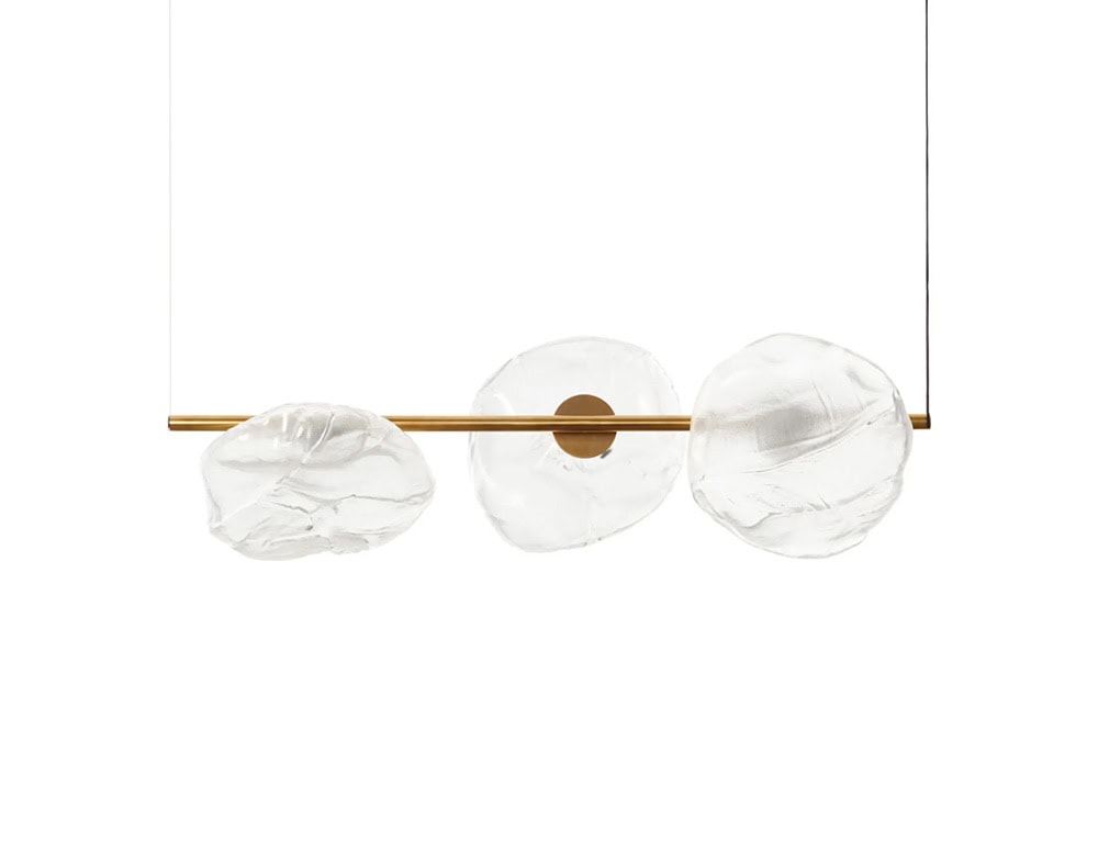 Boc Stem Suspension Light features a brass horizontal rod paired with three large, organic glass diffusers. The design combines artisan-crafted detail with modern symmetry in a suspended linear arrangement.