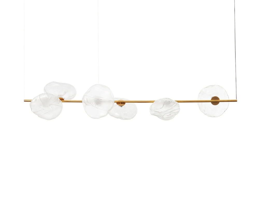 Boc Stem Suspension Light features a brass horizontal stem supporting five organic, hand-formed glass orbs. The arrangement evokes fluidity and balance, suspended in an airy minimalist scene with striking material contrast.