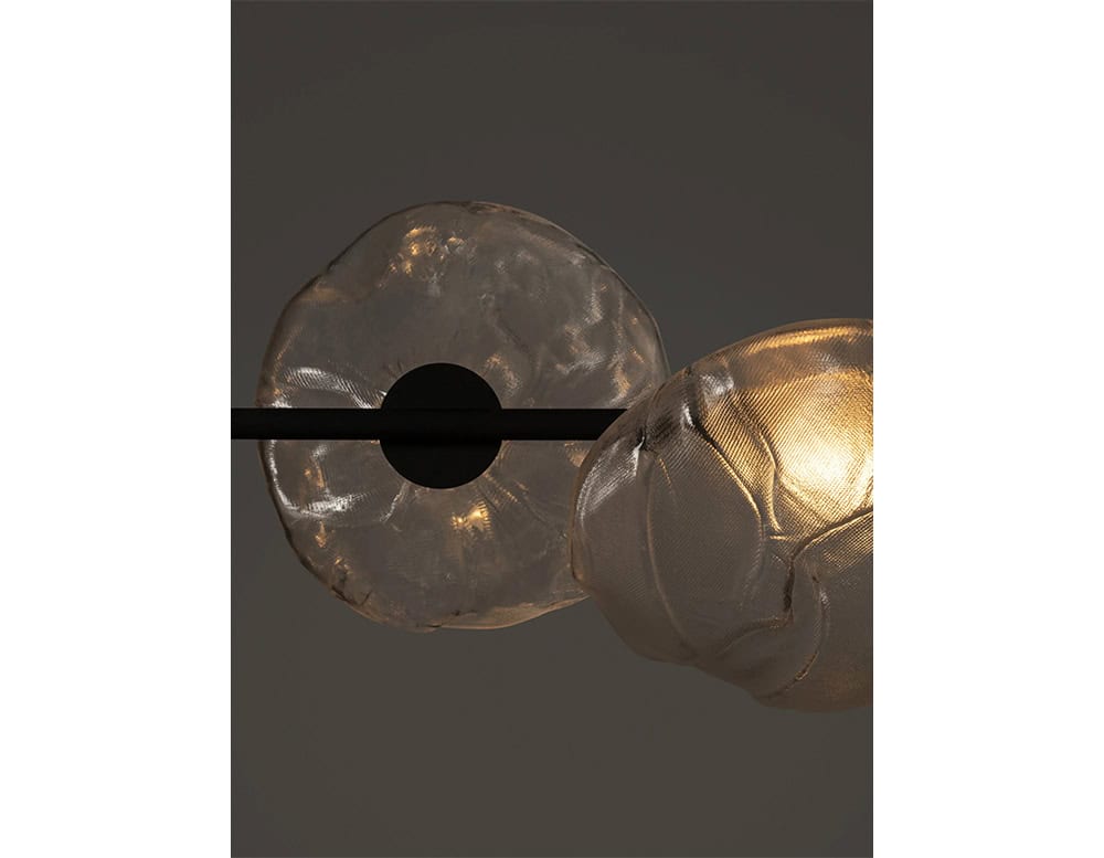 Boc Stem Suspension Light showcases glowing hand-formed glass orbs suspended on a sleek black rod. The subtle illumination highlights the textures and curvature of each glass piece with understated elegance.