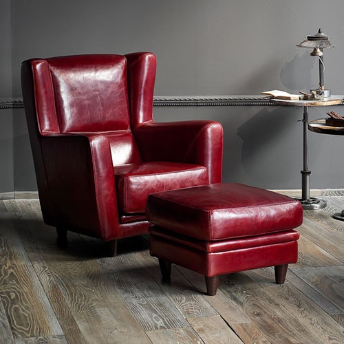 Red Bergère armchair and pouf. One-piece frame. Feet in walnut-stained beech. Decorative piping in the same shade of leather.