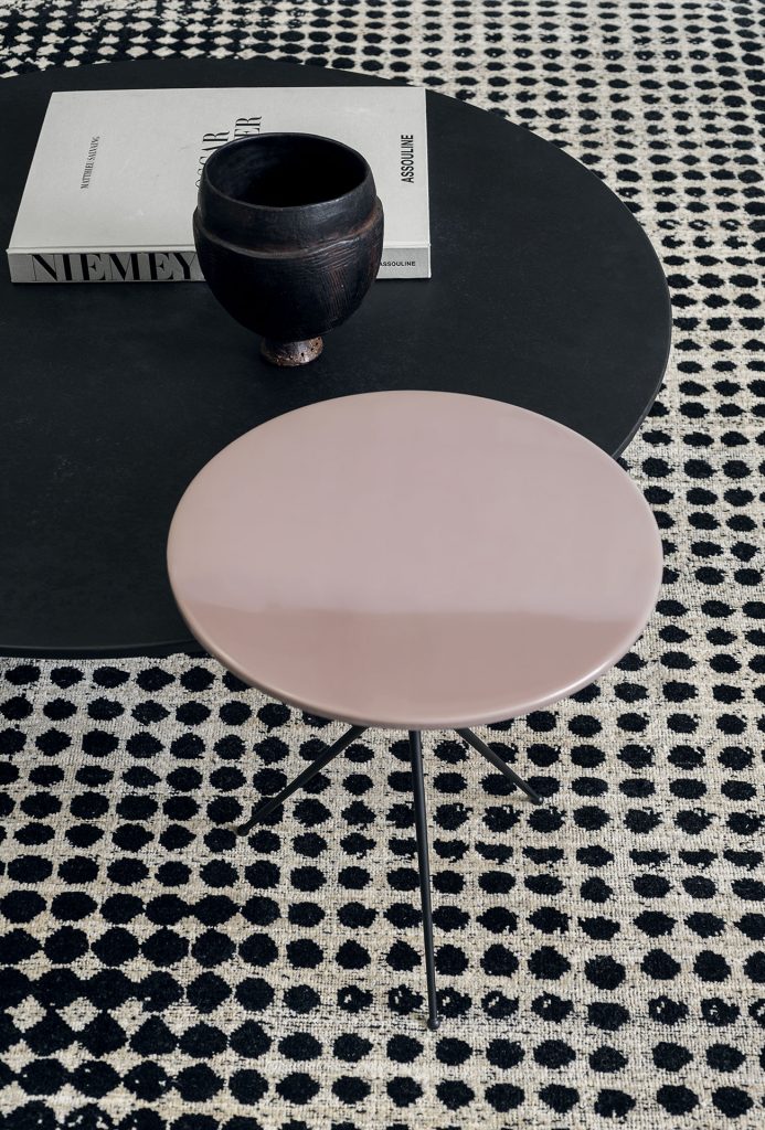 A Scarlet Pois rug, made of wools, hand-dyed in white and black circles pattern with two tables as decoration.