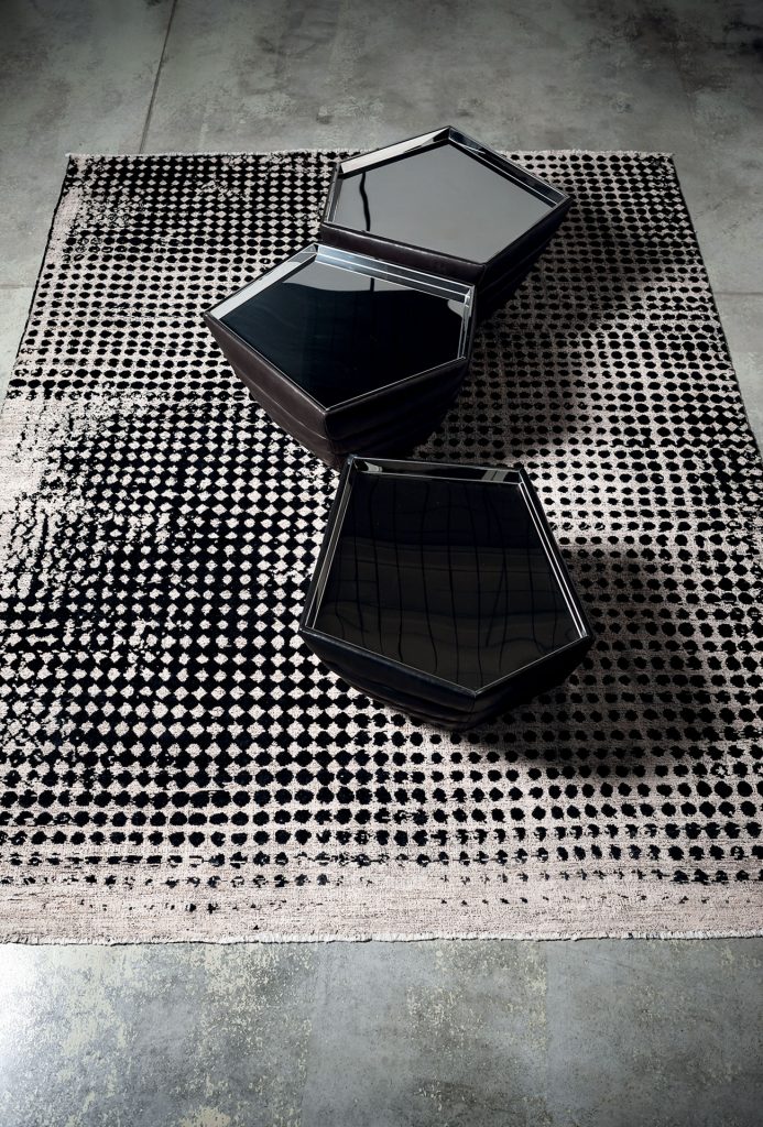 A Scarlet Pois rug, made of wools, hand-dyed in white and black circles pattern with two tables as decoration.