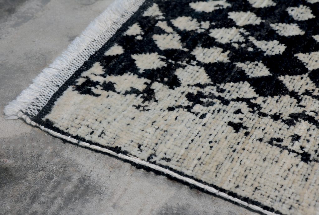 A Scarlet Pois rug, made of wool, hand dyed with a black and white diamond pattern in a dining room.