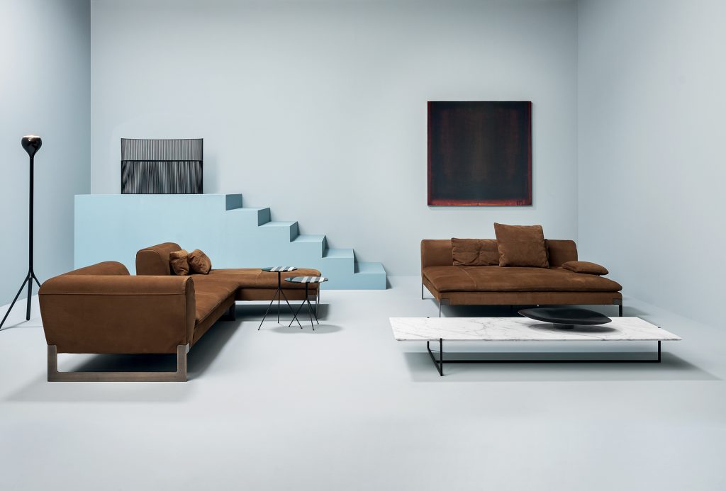 A brown Victor sofa divided into three modules, a module for two wiht low back, one for two with left low back, a dormeuse with low back. Brassed metal feet and support hook. Covers in leather in a dining room.