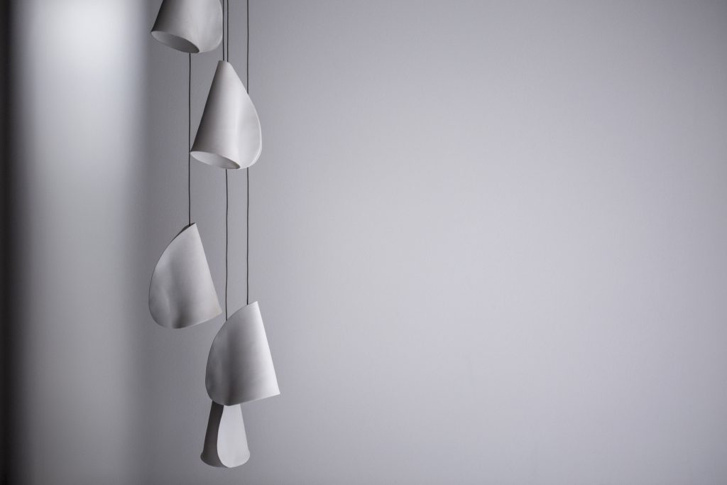 A Twenty One lamp made of porcelain, blown borosilicate glass, braided metal coaxial cable, electrical components, brushed white powder coated canopy on a white background.