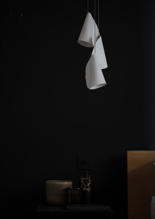 A Twenty One lamp made of porcelain, blown borosilicate glass, braided metal coaxial cable, electrical components, brushed white powder coated canopy on a black background.