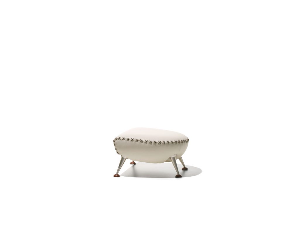 DS hundred two- eleven footstool. White and black upholstered shell on a white background.
