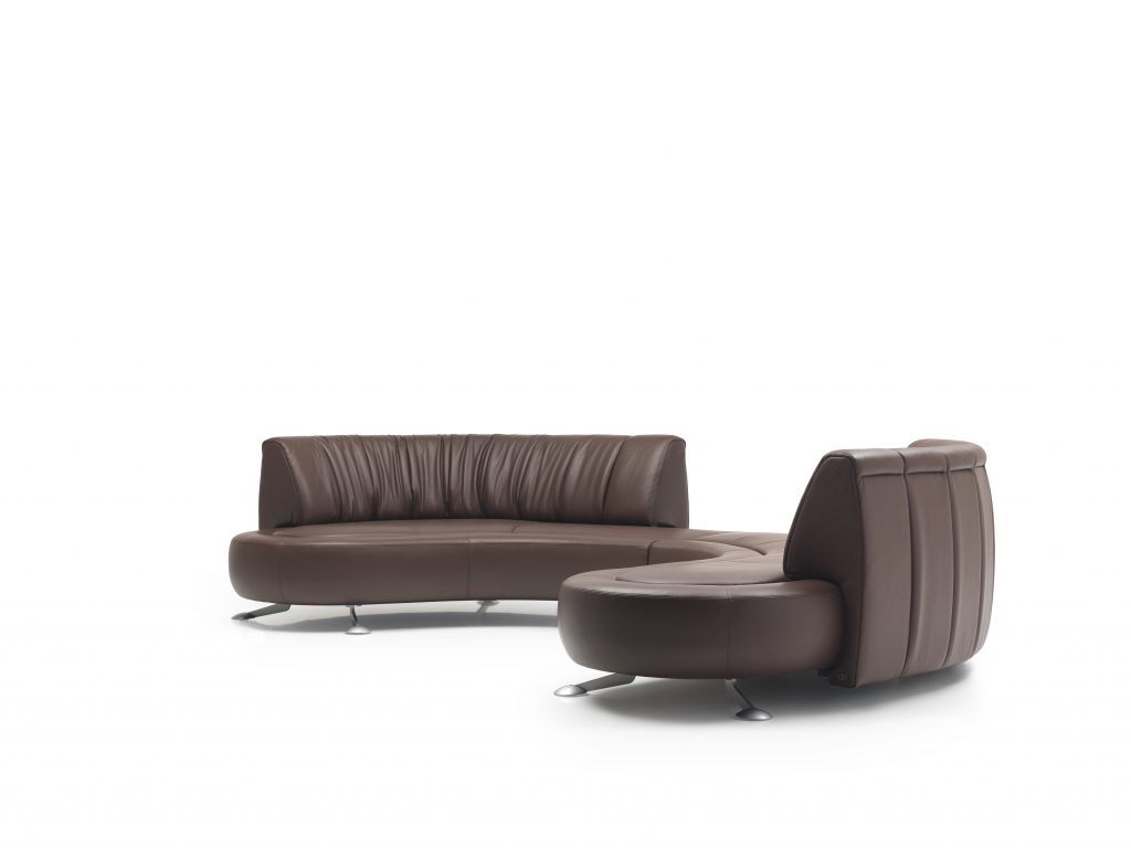 A brown DS-thousand sixty four sofa. rounded seat with backrest, cover in leather and steel legs on a white background.