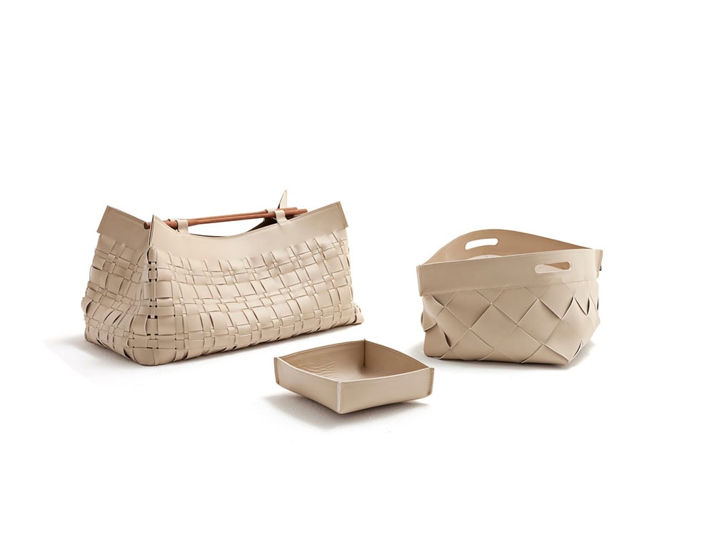 A studio shot of the 10th Baskets Tray collection showcasing three variations with intricate woven leather designs structured shapes and neutral tones