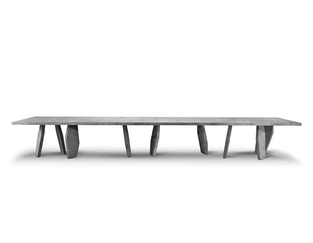 A 10th Joint Dining Table with a long, dark rectangular top and multiple cylindrical legs is shown from a low angle against a white background