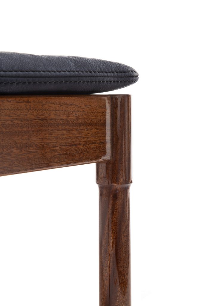 Closeup of Vieste Pouf: Rectangular pouf with a black cushioned top and four brown legs on a white background.