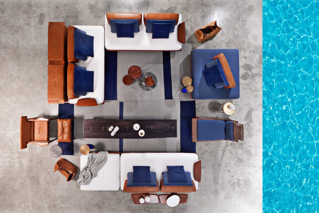 Vieste Pouf: Rectangular pouf with a brown cushioned top and four brown legs in a living room.