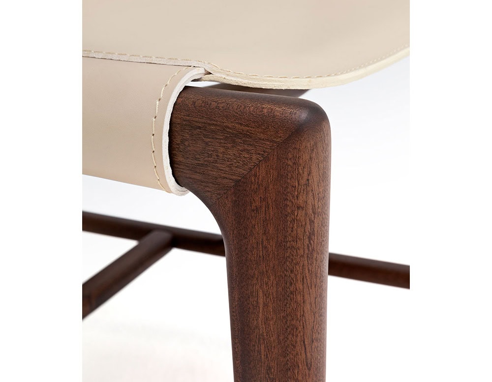 Closeup of Levante Chair. Structure in brown wood, seat and backrest in white leather on a white background..