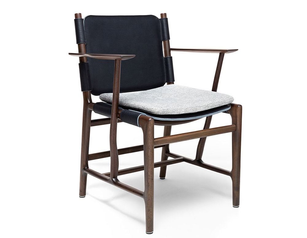 Levante Chair. Structure in brown wood, seat and backrest in black leather with gray cushions on a white backrground.