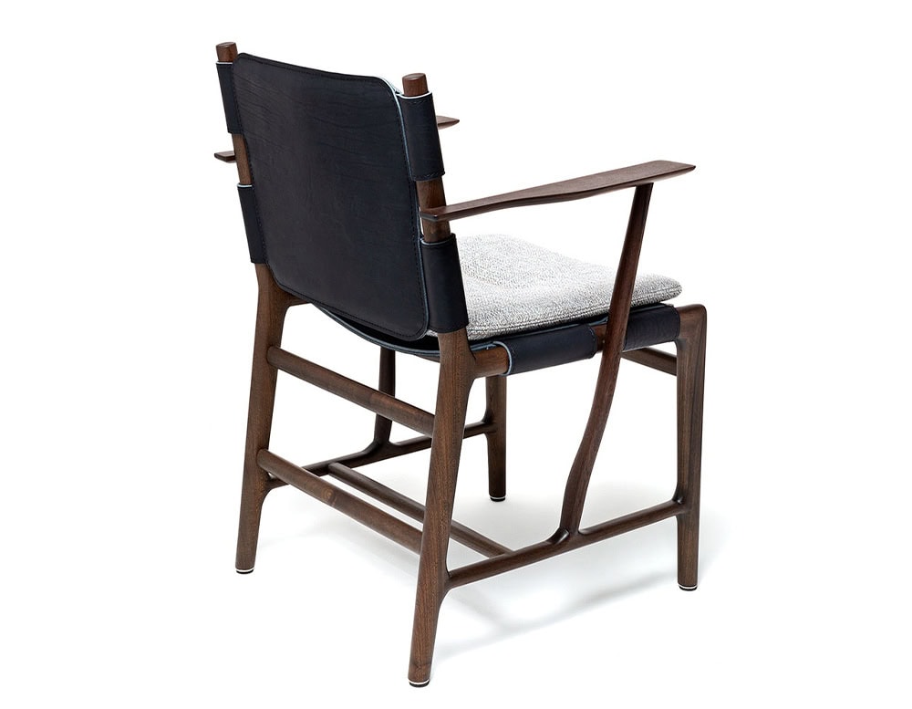 Levante Chair. Structure in brown wood, seat and backrest in black leather with gray cushions on a white backrground.