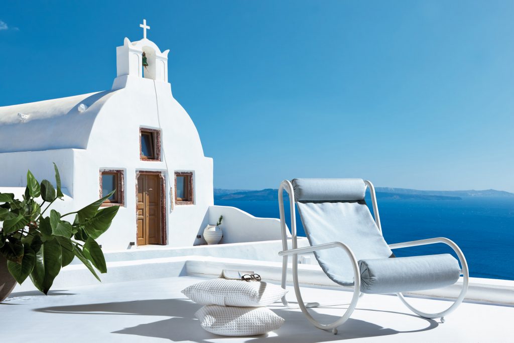 locus solus armchair in white in front of a churge next to the ocean