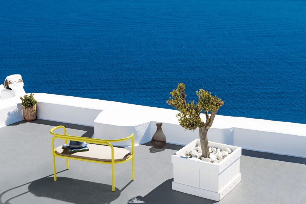 locus solus loveseat in yellow next to a plant on a terrace facing the sea