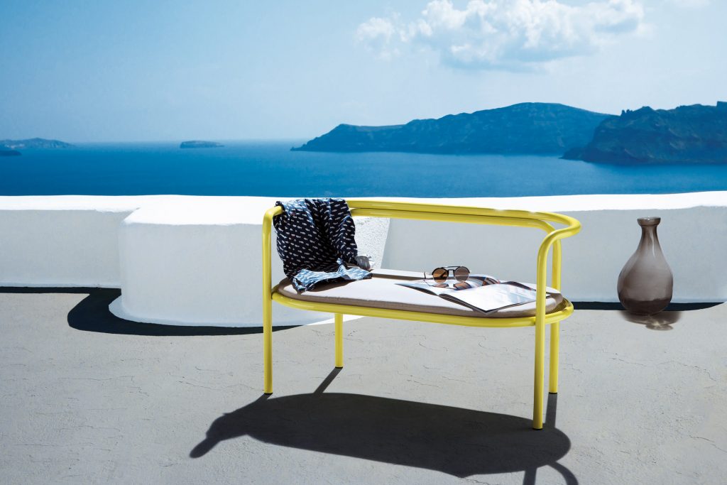 locus solus loveseat in yellow with a white cushion with an oceanview in the background