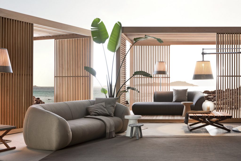 palau outdoor sofa in beiege net to two cabanas and some plans while also surrounded by furniture