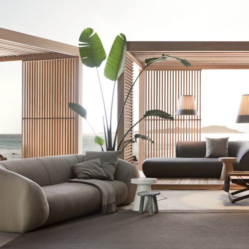 palau outdoor sofa in beiege net to two cabanas and some plans while also surrounded by furniture