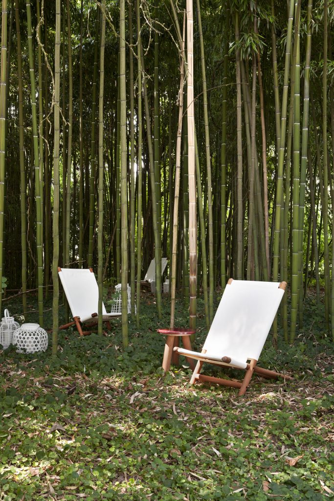 paraggi beach chair in white cover and wood construction next to some bamboo trees