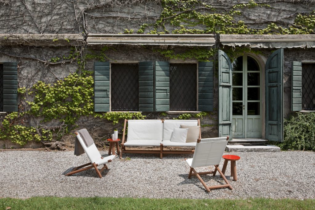 paraggi beach chair in white fabric next to a sofa outside a house