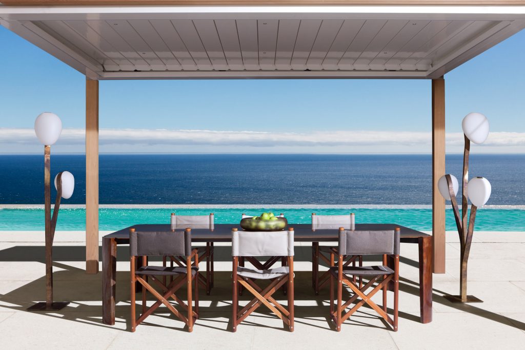paraggi yatch chairs in two different colors on a dining room setting outdoors with a pool and ocean background