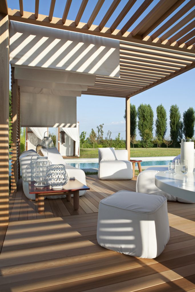 stone pouf in white next to a pool surrounded by other furniture