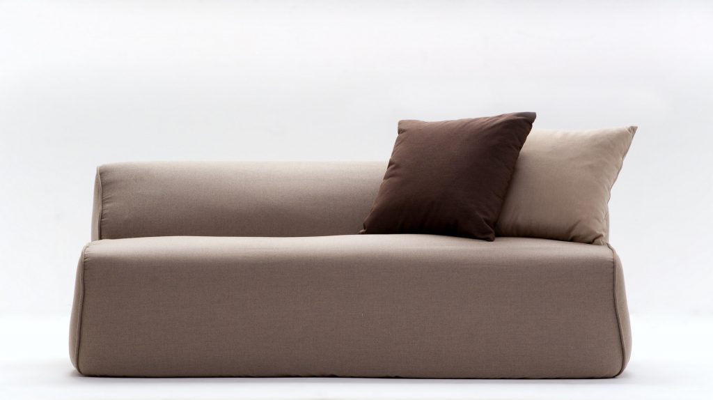 soft sofa in beige with a brown pillow on a white backgroun