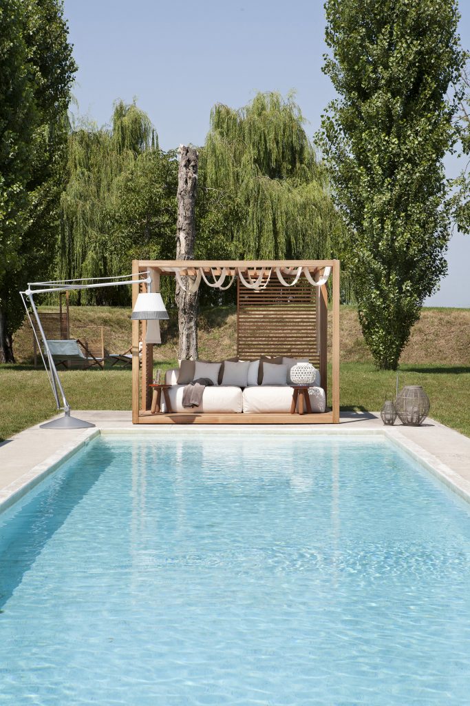 zen light cabana in front of a pool, with a gray sofa and a pool lamp