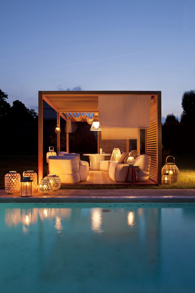 zen light cabana in mohagony next to a pool, inside the zen light we see outdoor furniture