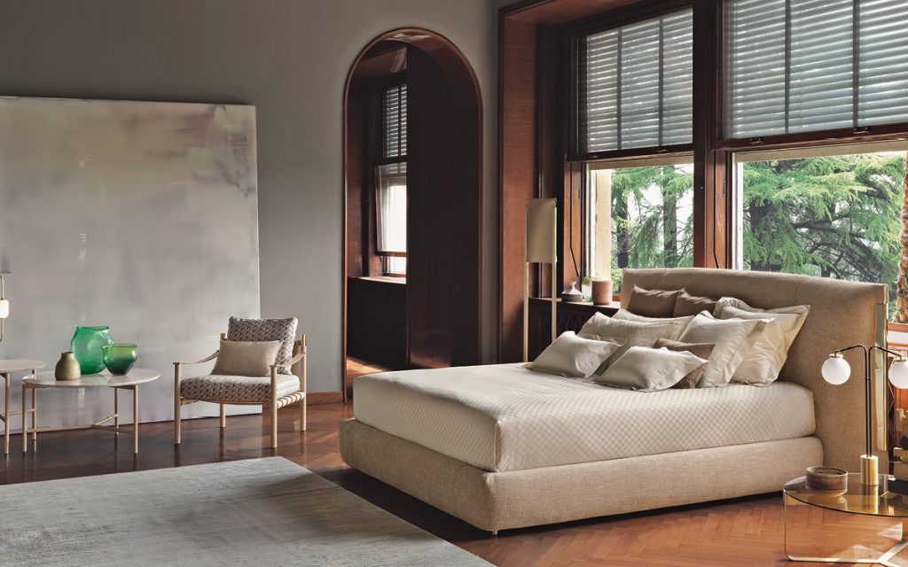 amal bed in beige in front of a window and a next to a beige chair