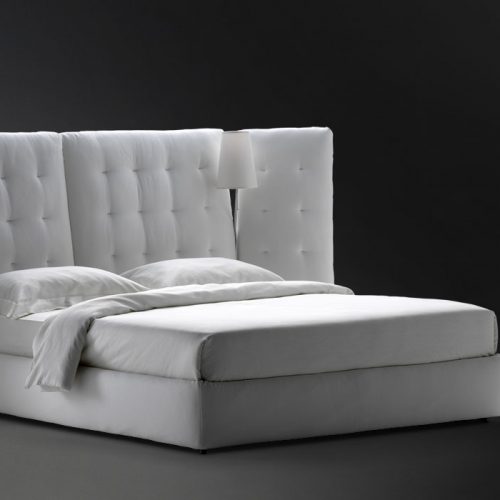 angle bed with quilted white headboard and side panels with white sheets
