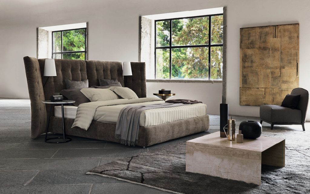 angle bed with a quilted olive headrest in a room setting next to window
