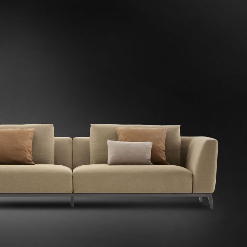 Olivier C sofa upholstered in brown fabric and four legs in steel on a black background.
