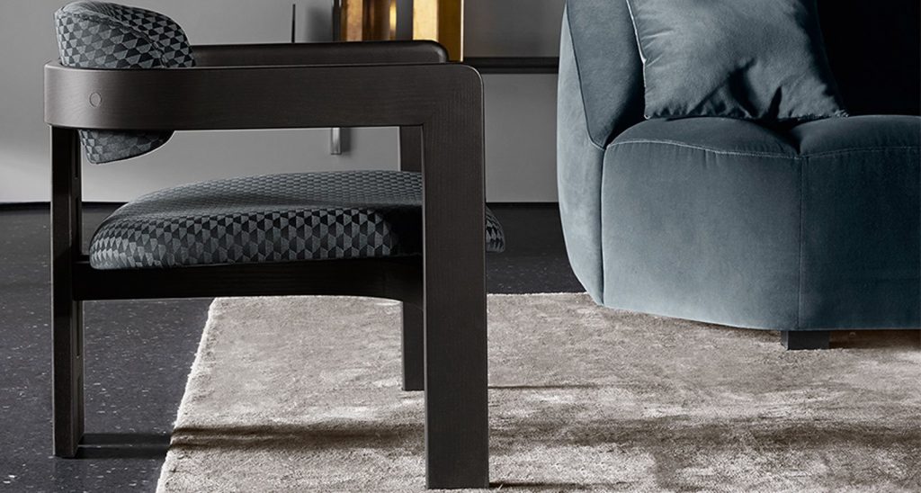 Side view of Four Hundred Seventeen chair in dark grey next to a blue sofa on a grey rug