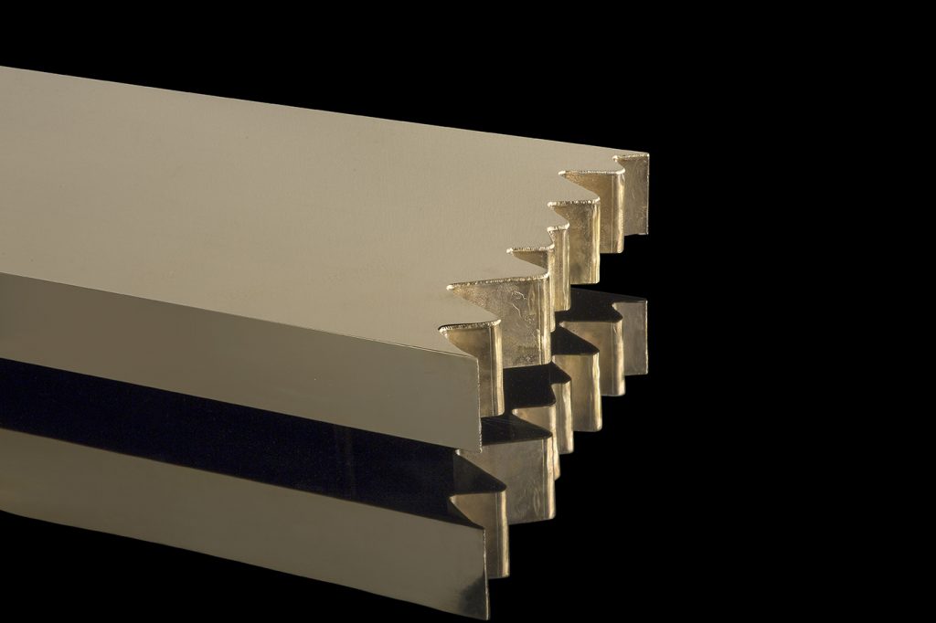 Closeup of rectangle Be Mine coffee table. Finish in brass with pointed edges on a black background.