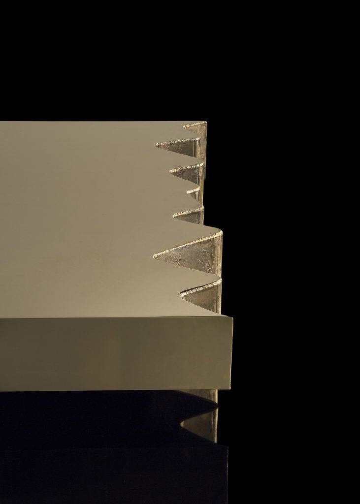Closeup of rectangle Be Mine coffee table. Finish in brass with pointed edges on a black background.