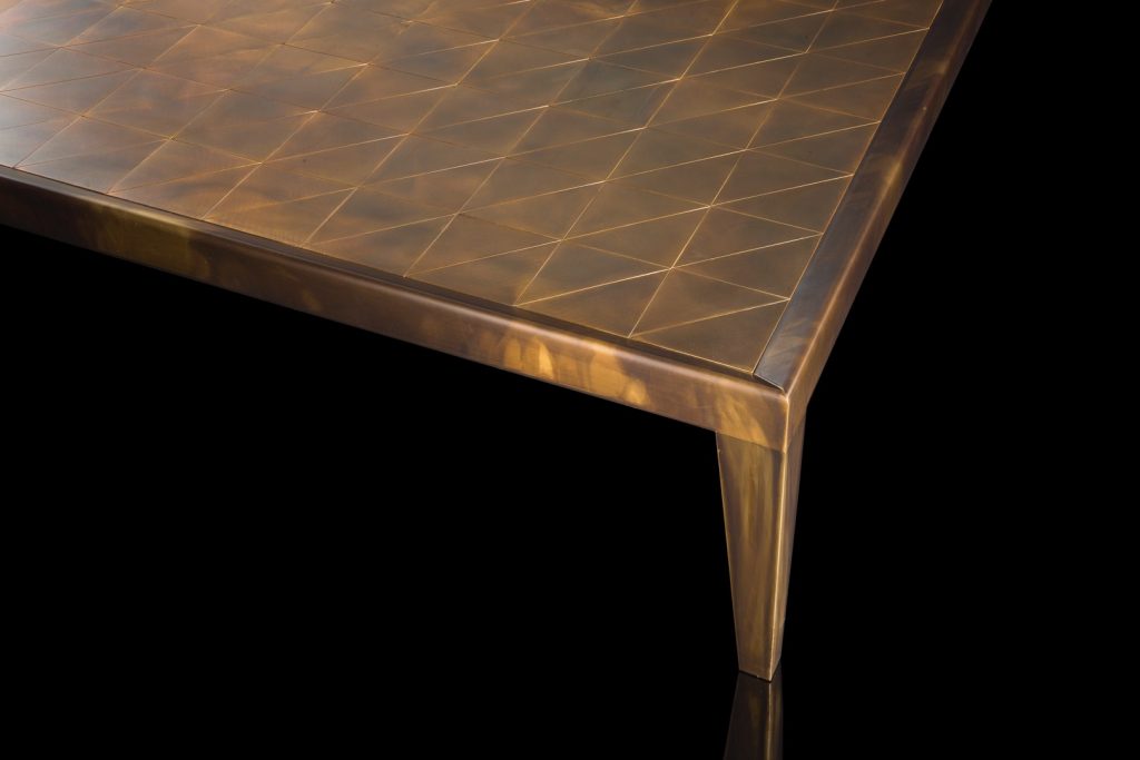 Square D Code Table top and four legs in brass on a black background.
