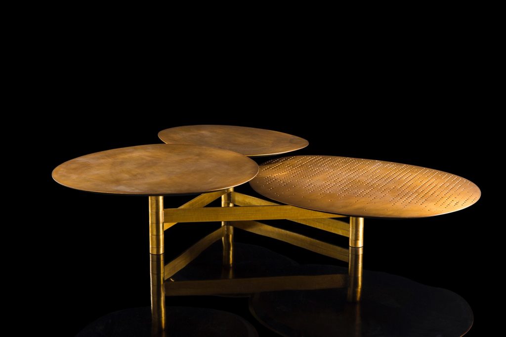 Galaxy table with three round giratory tables made of metal and brass on a black background.