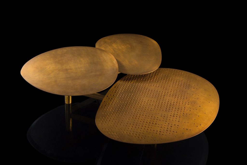 Galaxy table with three round giratory tables made of metal and brass on a black background.