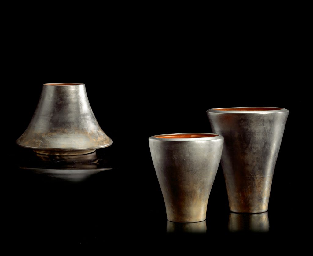Three H Vases made of porcelain stoneware, inside is color red, outside is color silver, two large cone vases and one long bowl on a black background.