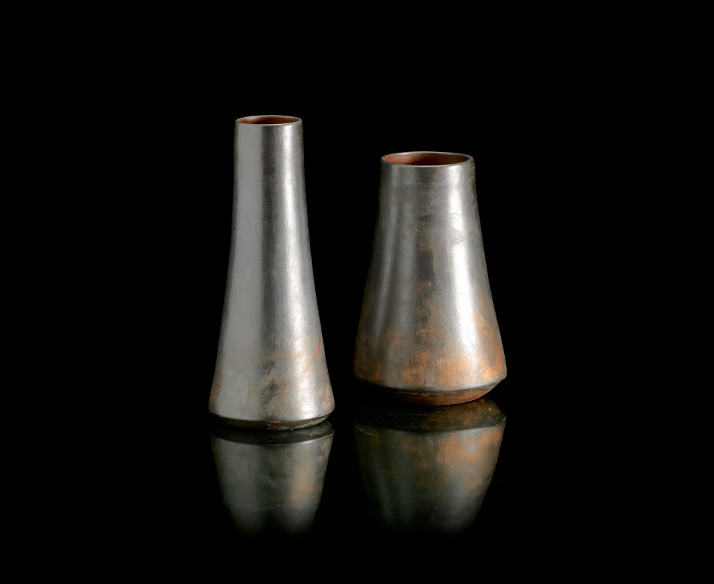 Two H Vases made of porcelain stoneware, inside is color red, outside is color silver, one small spool vase and one long spool vase on a black background.