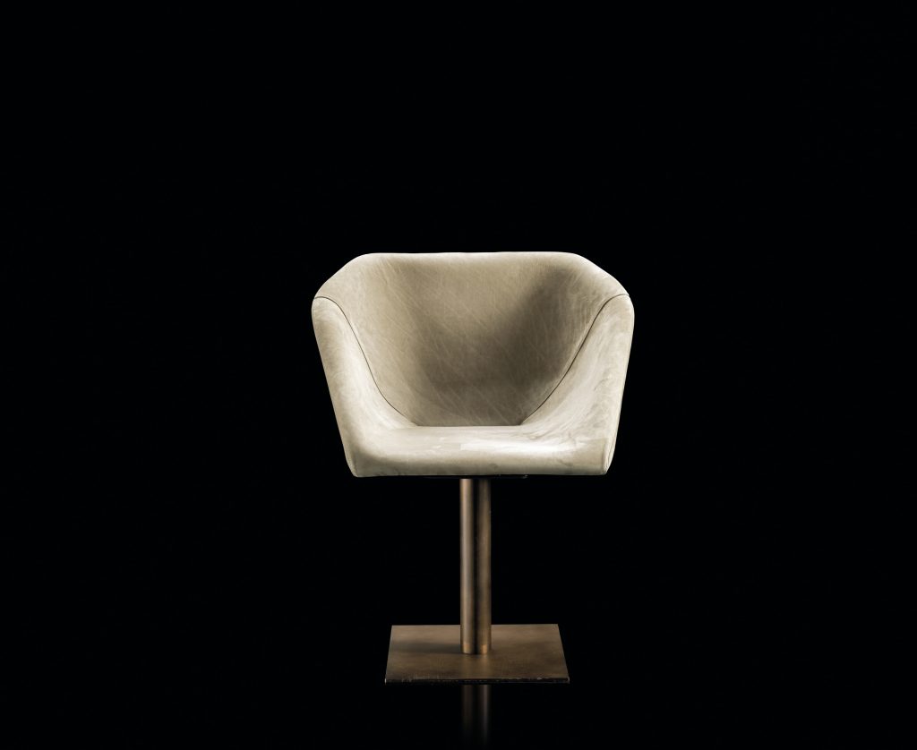 Hexagon chair, upholstered in white leather and central leg finished in brass on a black background.