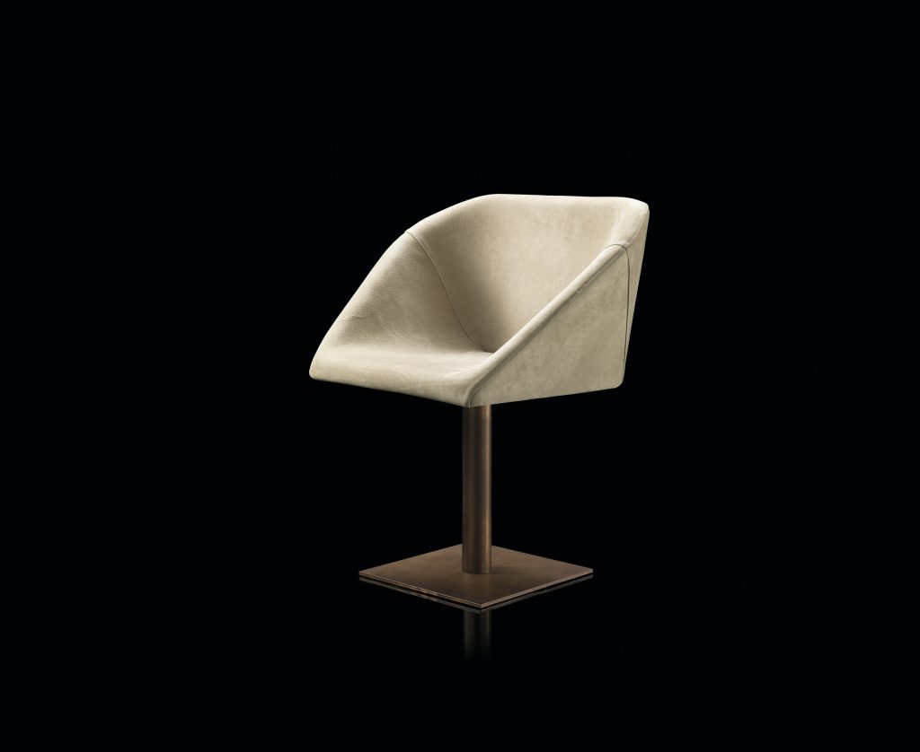 Hexagon chair, upholstered in white leather and central leg finished in brass on a black background.