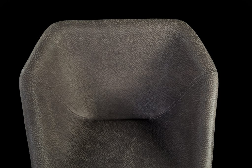Hexagon chair, upholstered in gray leather and central leg finished in brass on a black background.
