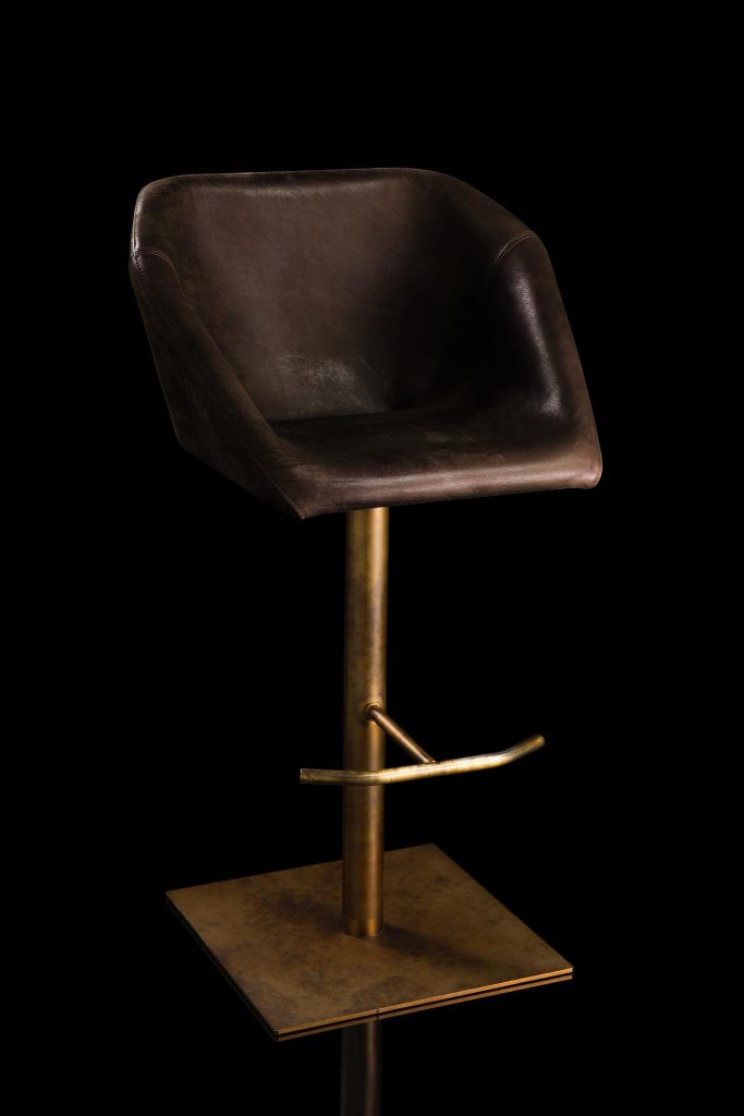 Hexagon stool, padded seat upholstered in brown leather and central steel leg on a black background.