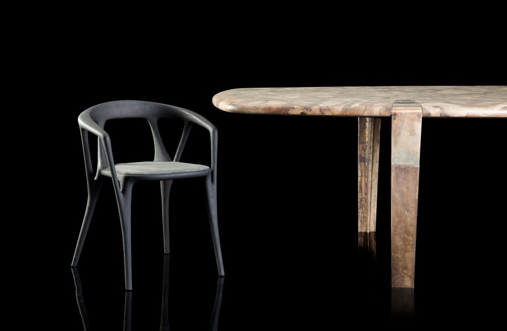 Closeup of Oxymoron Table Structure steel frame with four legs in sandcasting, bronze. Top in natural solidwood on a black background.